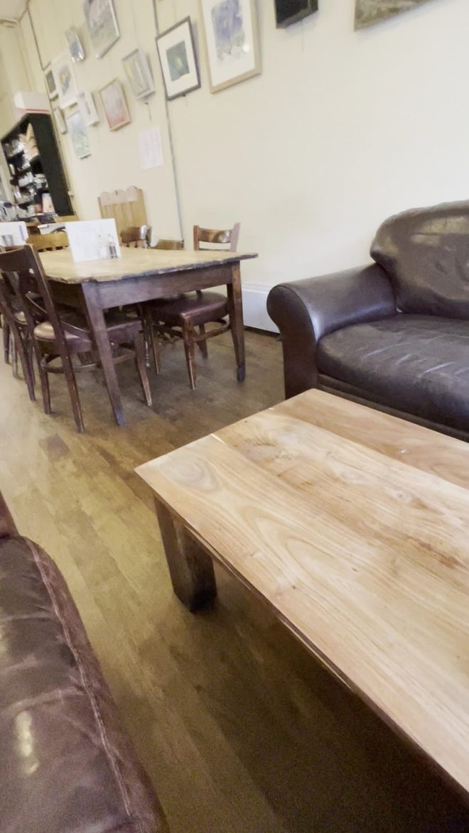 Interior with leather sofas, a wooden coffee table and a dining table with chairs under framed pictures.